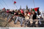 Palestinske demonstranter forsøker å forsere gjerdet.